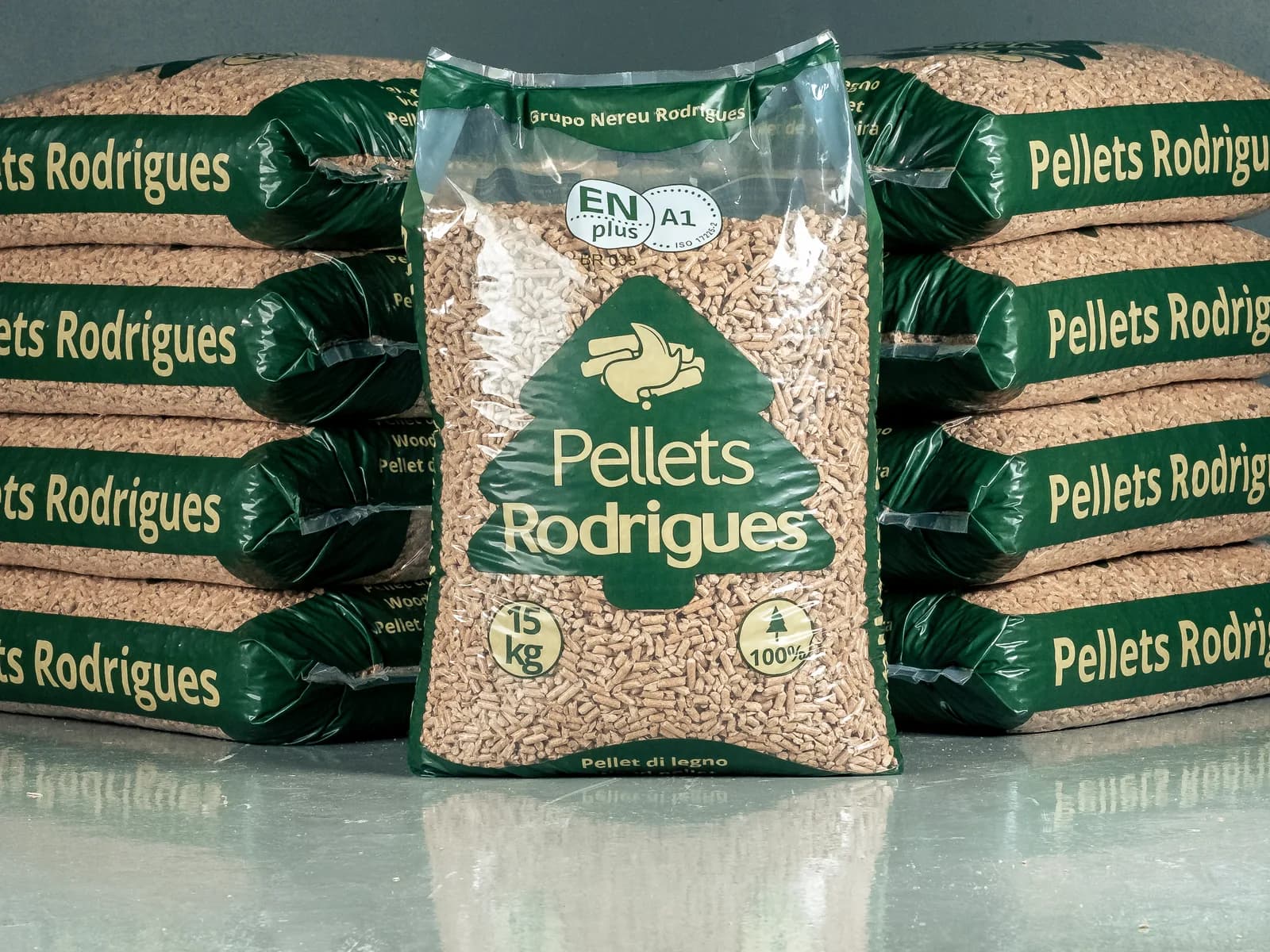 Saco de 15 kg de Pellets Rodrigues em pé, com o selo ENplus A1, entre duas pilhas de sacos