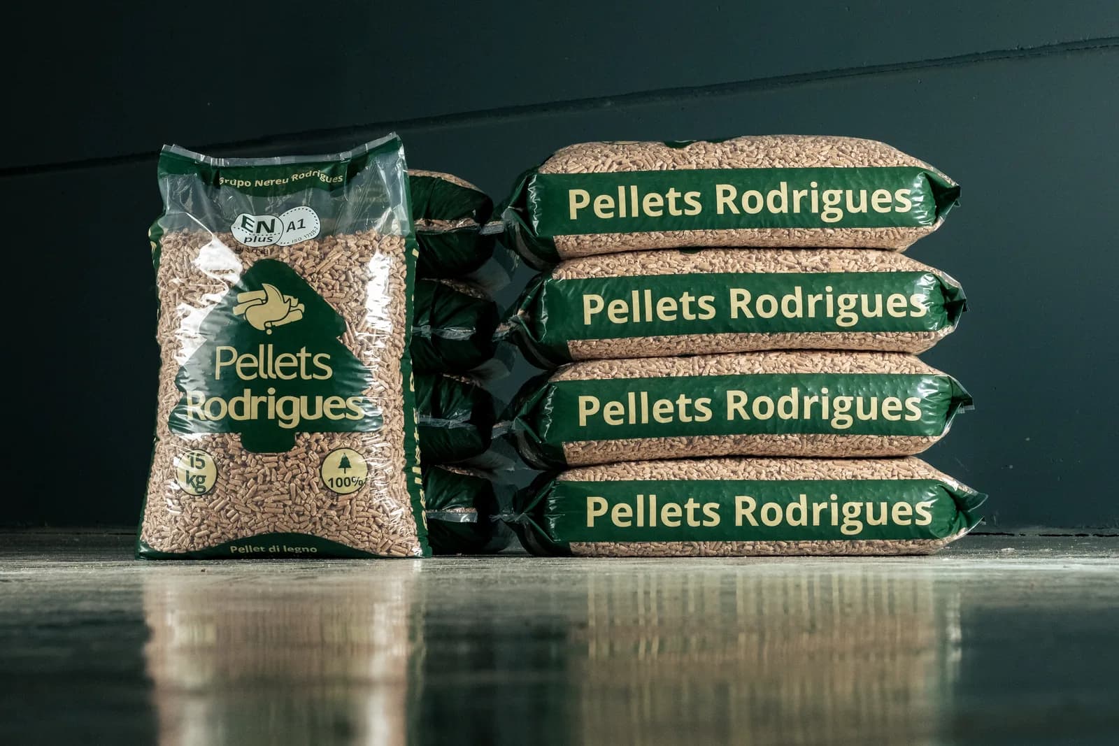 Saco de 15 kg de Pellets Rodrigues com selo ENplus A1 ao lado de uma pilha de sacos
